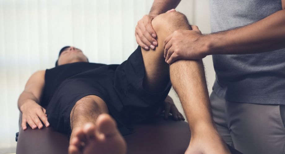 A patient lays on an exam table while being evaluated by a physical therapist for blood flow restriction therapy